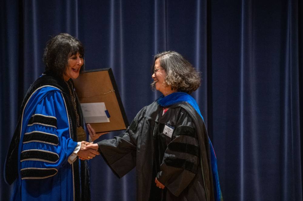 President Mantella shakes hands and presents woman with large certificate award